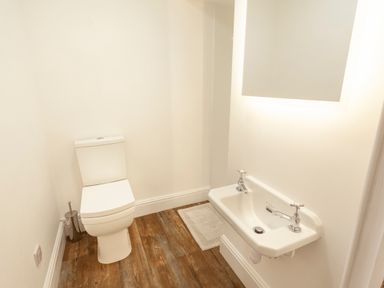 A small bathroom with a toilet and a wall-mounted sink with two taps at Crablake Farmhouse in Exminster