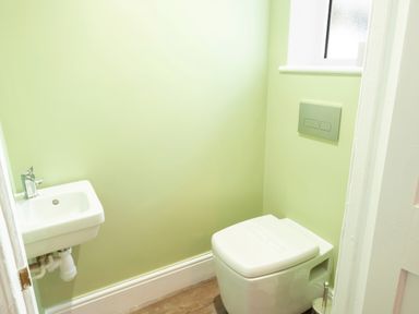 A small bathroom with a wall-mounted sink and a toilet at Crablake Farmhouse in Exminster