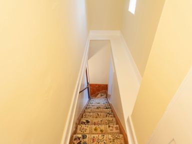 A staircase with floral patterned carpet and yellow walls at Crablake Farmhouse in Exminster