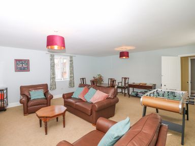 A living room with brown leather sofas a coffee table a foosball table and a dining table with chairs at Crablake Farmhouse in Exminster