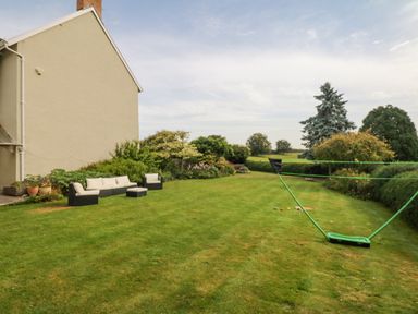 A backyard with lawn furniture and a badminton net at Crablake Farmhouse in Exminster