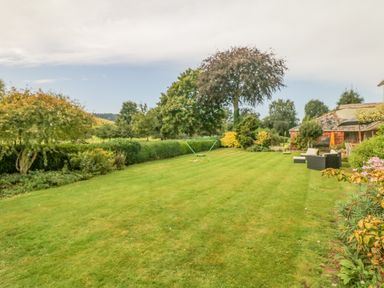 A garden with lawn chairs and trees at Crablake Farmhouse in Exminster