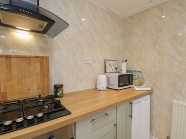 A kitchen countertop with a gas stove kettle microwave and a refrigerator at The Nook in Whitby