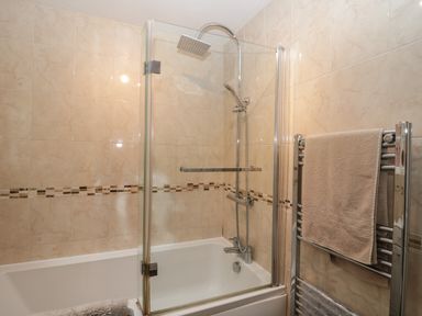 A bathroom with a bathtub shower combination and a towel rack with towels at The Nook in Whitby