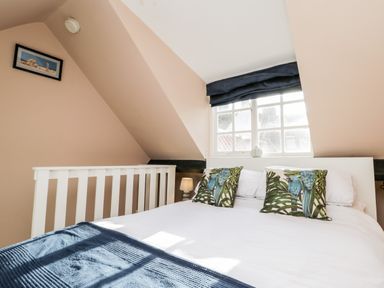 A bedroom with a bed that has two pillows with bird designs and a window with dark blinds at The Nook in Whitby
