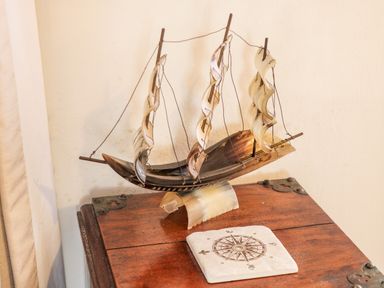 A model sailboat with curved sails on a wooden table next to a compass design tile at The Nook in Whitby