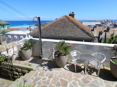 A terrace with a table and chairs overlooking the sea at Heron St Ives