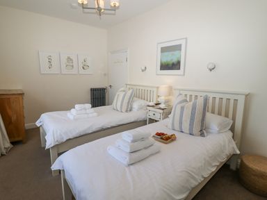 A bedroom with two single beds and a nightstand with a lamp in between at Whistler in St Ives