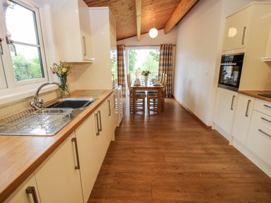 A kitchen with wooden countertops and cabinets and a dining table with chairs at The Log Cabin in Newnham Bridge near Tenbury Wells