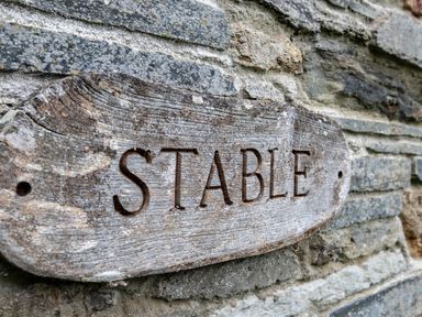 A wooden sign with the word Stable on a stone wall at Stable Cottage in Port Isaac