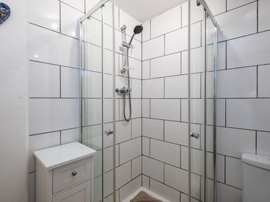 A bathroom with a corner shower enclosure a white cabinet and a toilet at Stable Cottage in Port Isaac