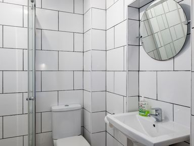 A bathroom with a toilet sink round mirror and handwash at Stable Cottage in Port Isaac