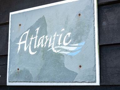 A weathered sign with the word Atlantic mounted on a dark wooden wall at Atlantic Lodge in Port Isaac