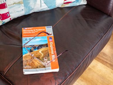 A leather couch with a pair of glasses and a Newquay and Padstow explorer map at Gull Lodge in Port Isaac
