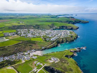 An aerial view of a coastal town with houses green fields and cliffs by the sea at Gull Lodge in Port Isaac