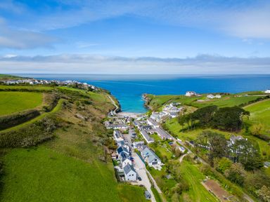 A coastal village with houses green fields and a view of the ocean at Gull Lodge in Port Isaac