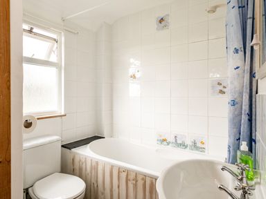 A bathroom with a bathtub shower toilet sink and a window at Campion Lodge in Port Isaac