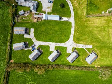 An aerial view of small buildings aligned with pathways in a grassy area at Harbour Lodge in Port Isaac