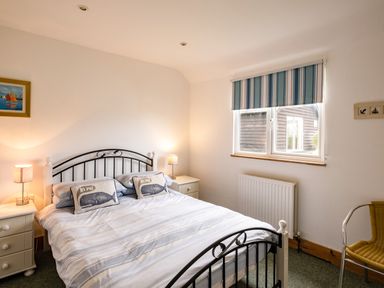 A bedroom with a double bed with pillows and two bedside tables with lamps at Puffin Lodge in Port Isaac