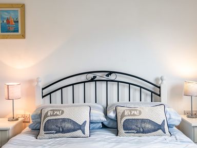 A bedroom with a double bed that has striped bedding and two pillows with whale designs on it at Puffin Lodge in Port Isaac