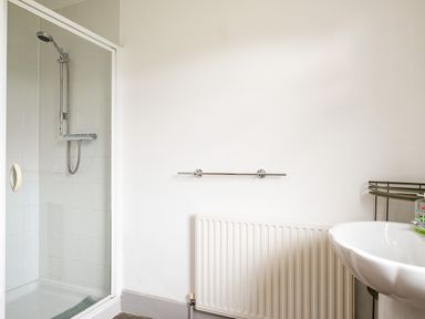 A bathroom with a shower enclosure radiator towel rail and a pedestal sink at Puffin Lodge in Port Isaac
