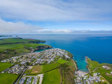 A coastal town with houses fields cars and blue ocean at Puffin Lodge in Port Isaac