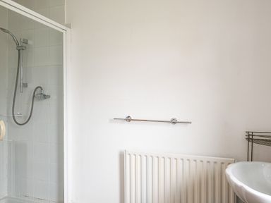 A bathroom with a shower enclosure radiator and a sink at Dolphin Lodge in Port Isaac