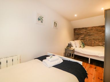 A bedroom with two single beds a bedside table and framed starfish artwork on the wall at Spindrift in Polperro