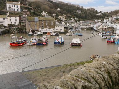 A harbor with moored boats and houses on hills in the background at Spindrift in Polperro
