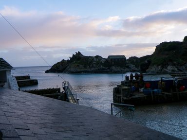 A small harbor with a rocky island and buildings by the water at Spindrift in Polperro