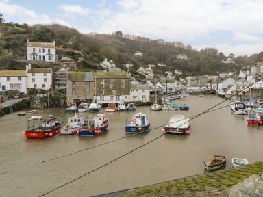 A harbor with boats moored near buildings and hills in the background at Spindrift Polperro