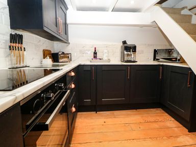 A kitchen with black cabinets wooden floor and kitchen appliances at Spindrift in Polperro