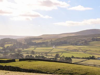 A rural landscape with green fields stone walls and hills in the distance at Cross View Cottage in Alston