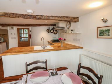 A kitchen and dining area with wooden beams and a wooden countertop at Cross View Cottage in Alston