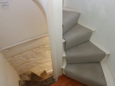 A narrow staircase with carpeted steps leading up and stone steps leading down at Cross View Cottage in Alston