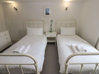 A bedroom with two single beds separated by a nightstand with a lamp at Cross View Cottage in Alston
