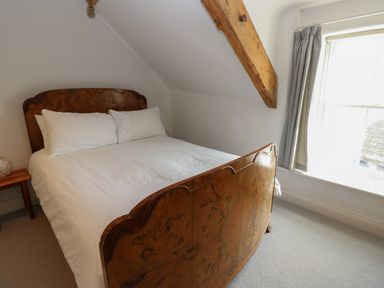 A bedroom with a wooden bed with white bedding near a window at Cross View Cottage in Alston