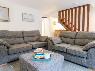 A living room with two grey sofas a grey ottoman with a tray of tea and biscuits and wooden stairs at Beach Road House in Hele Bay Ilfracombe