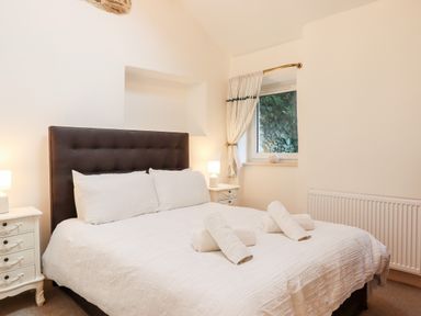 A bedroom with a double bed bedside tables lamps and a window at Beach Road House Hele Bay Ilfracombe