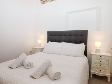 A bedroom with a bed with white linens and rolled towels on it and two bedside tables with lamps at Beach Road House Hele Bay Ilfracombe