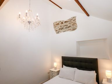 A bedroom with a bed a chandelier bedside tables and lamps at Beach Road House Hele Bay Ilfracombe