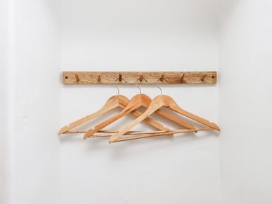 A set of three wooden hangers on a wooden peg rack against a white wall at Beach Road House in Hele Bay Ilfracombe