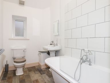 A bathroom with a toilet a sink and a bathtub with tiled wall at Beach Road House in Hele Bay Ilfracombe