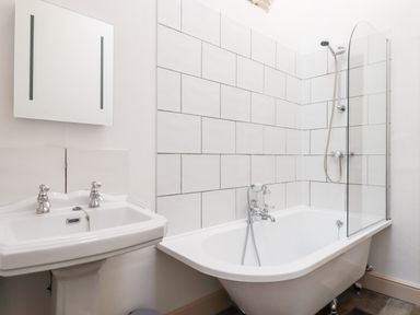 A bathroom with a pedestal sink and a clawfoot bathtub with a shower screen and tiled wall at Beach Road House Hele Bay Ilfracombe