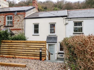 A row of houses with a gravel yard and wooden fence at Beach Road House in Hele Bay Ilfracombe
