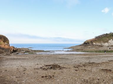 A beach with sand and rocks by the sea with cliffs on both sides at Beach Road House in Hele Bay Ilfracombe
