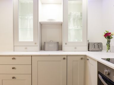 A kitchen countertop with cabinets glass doors a bread box a toaster and a vase of flowers at Beach Road House in Hele Bay Ilfracombe