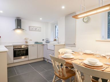 A kitchen with a dining table set with plates and glasses at Beach Road House in Hele Bay Ilfracombe