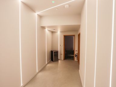 A hallway with vertical strip lighting and a small fridge near a doorway at Rynys in Llanddeiniolen near Llanrug
