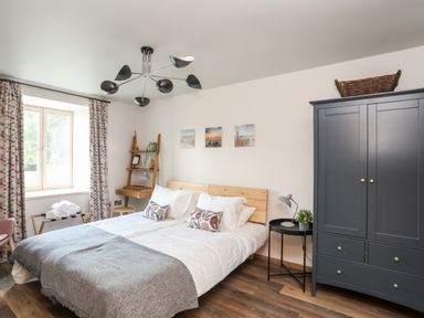 A bedroom with a double bed a black wardrobe and wooden flooring at Rynys in Llanddeiniolen near Llanrug